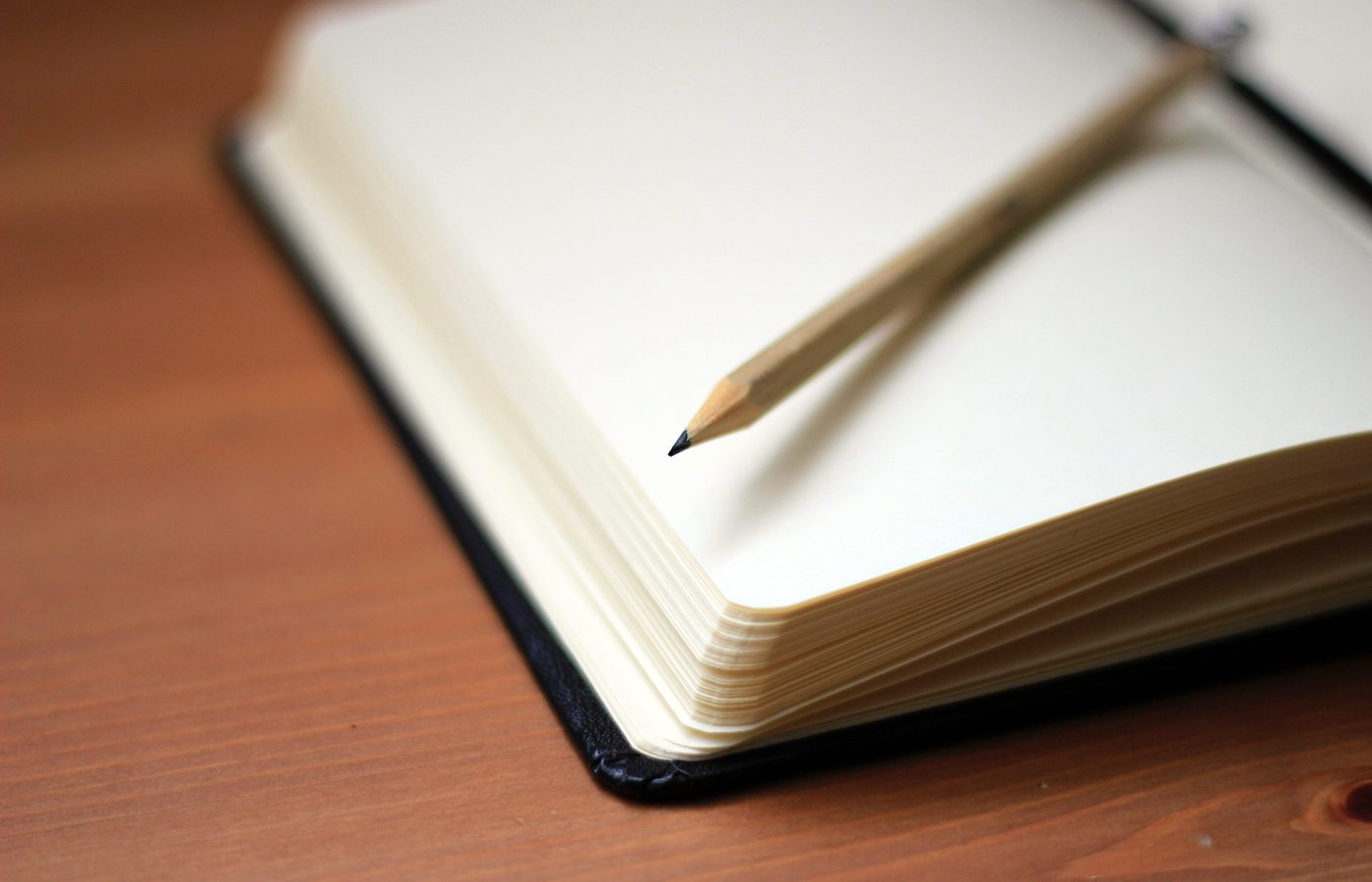 Carnet ouvert et crayon posés sur une table de travail